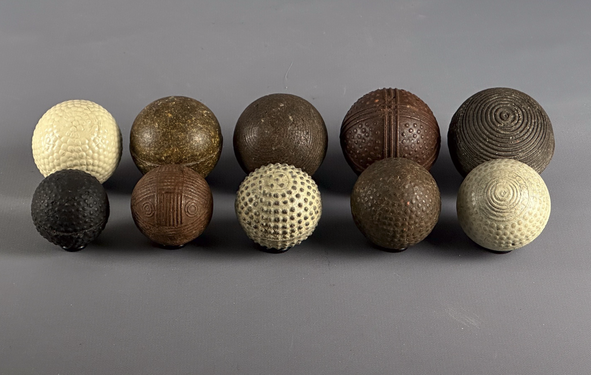 Nine play balls and one genuine golf ball showing size variations